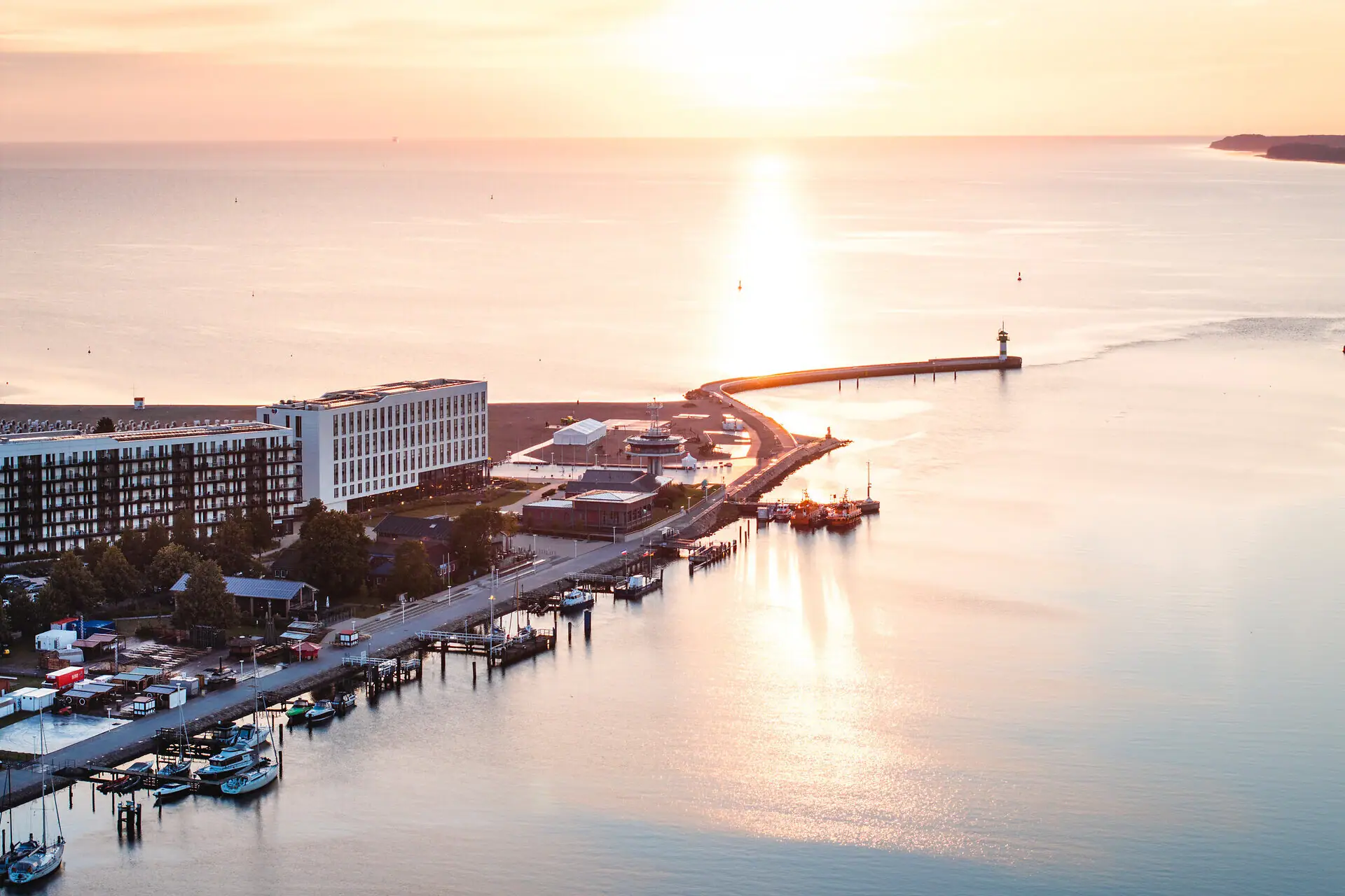aja Travemünde A body of water with a pier and buildings in the background.
