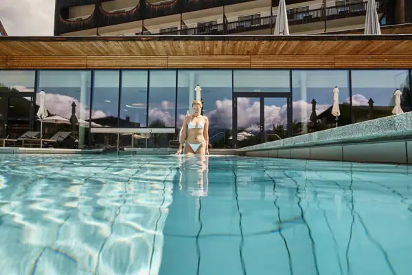 A woman in a swimming pool with the hotel in the background.