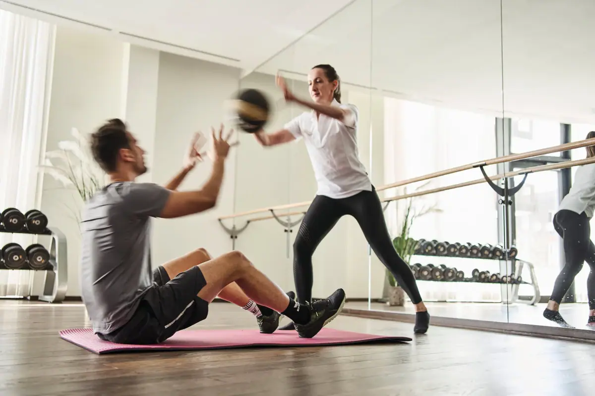 A man and a woman work out in a gym.