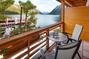 Double room balcony A balcony with table and chairs overlooking a lake.