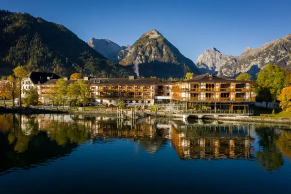 aja Fürstenhaus am Achensee A building next to a body of water with trees in the background.