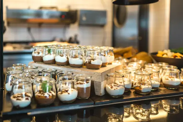 A group of small glasses filled with desserts.