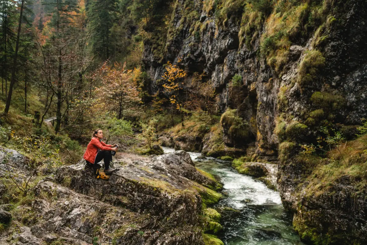 Hiking near Ruhpolding A woman is sitting on a rock by the river.