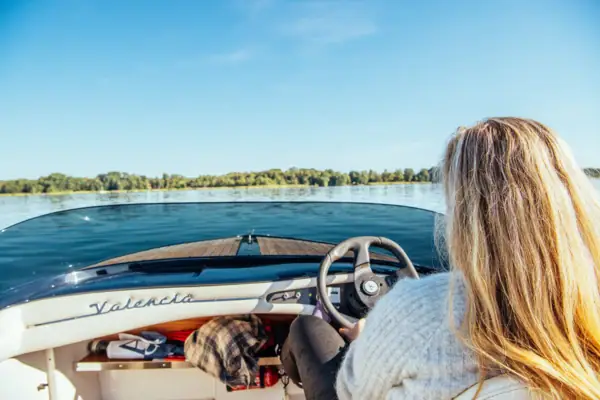 A woman sits in an e-boat and steers across the lake.