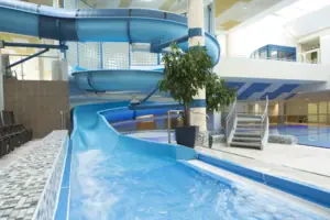 A water slide inside a building, above a swimming pool.