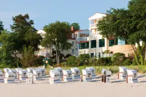 Eine Gruppe von Strandkörben am Strand mit dem aja Strandhotel Bansin im Hintergrund.