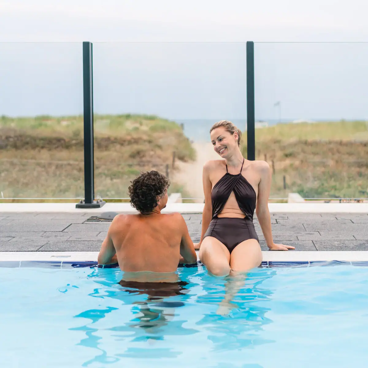 A man and a woman sit in a pool.