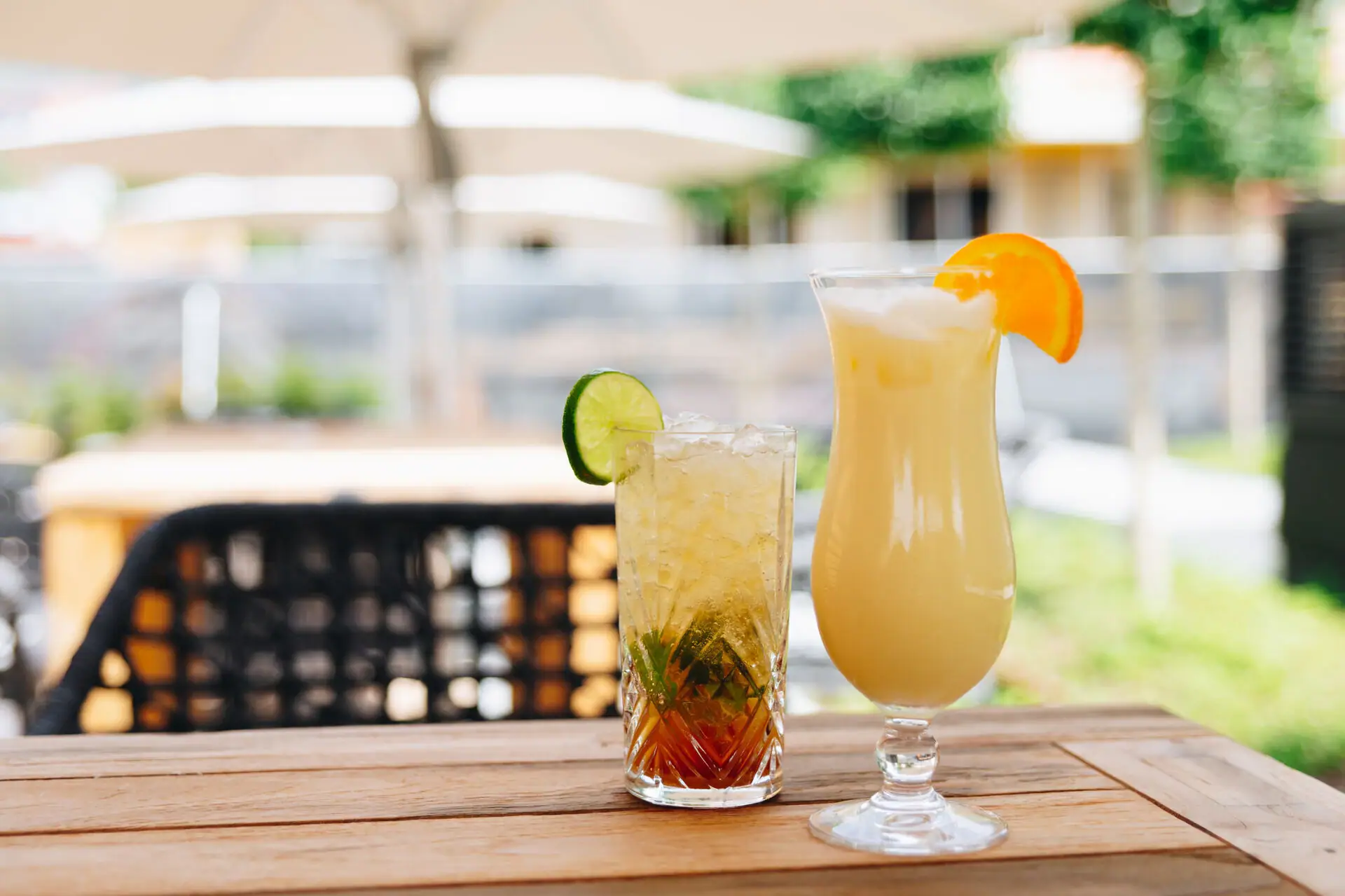 Two drinks on a table, one with a cocktail set and straw.