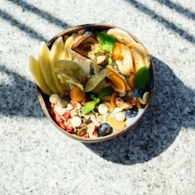 A bowl of smoothie, fruit slices, nuts and seeds