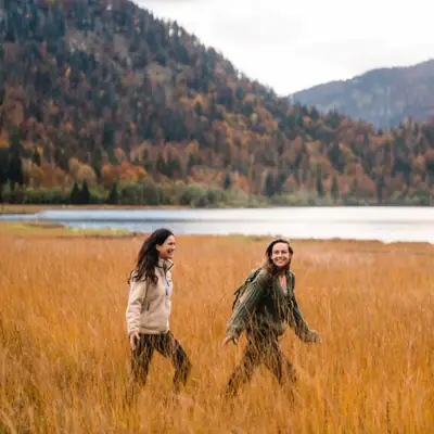 Two women walk through tall grass.