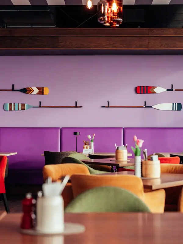 Ein Raum mit Tischen und Stühlen und einer lila Wand mit Rudern.