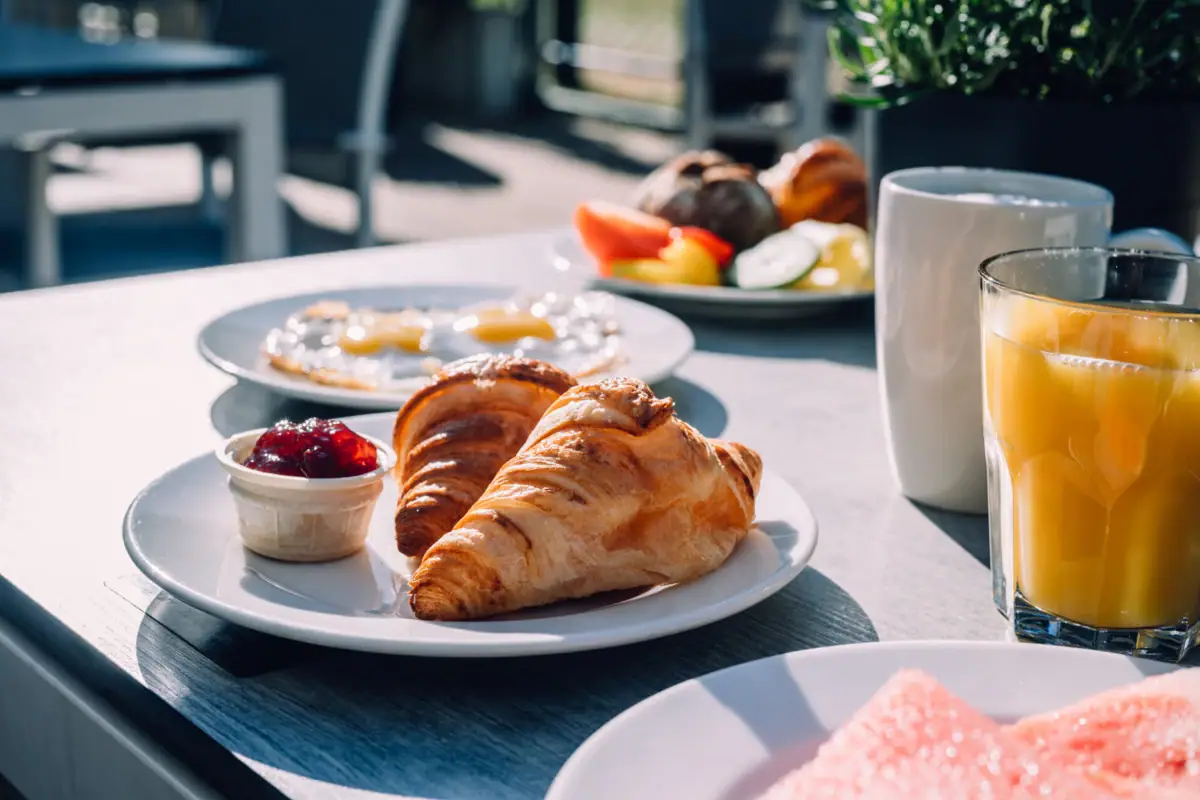 A plate of breakfast on a table, accompanied by a glass of juice.