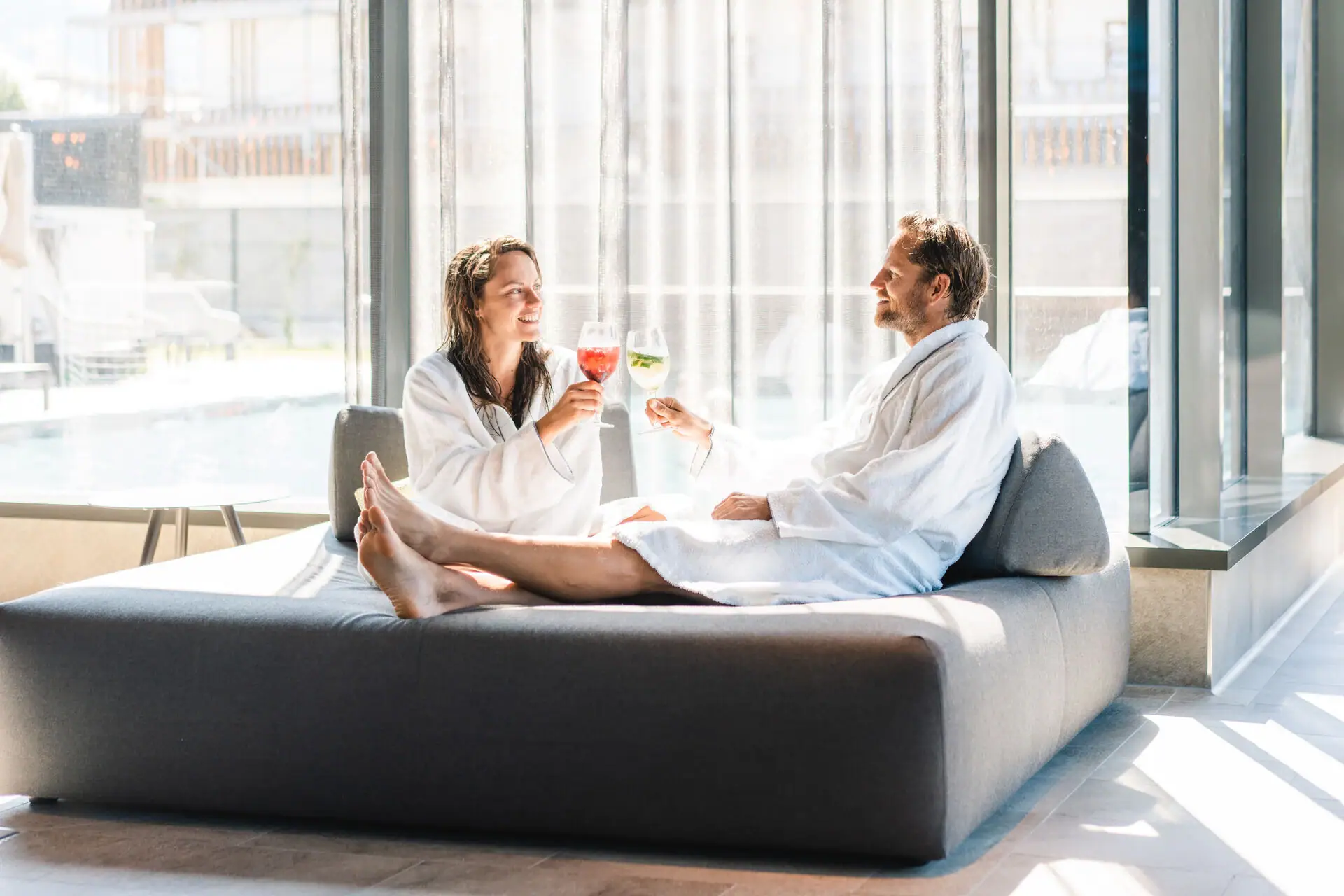 Couple bumps into each other.  A man and a woman in bathrobes are sitting on a sofa.