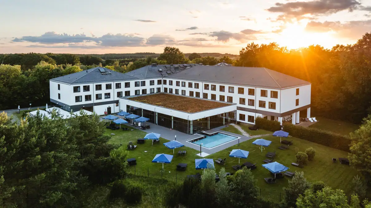 aja Bad Saarow A building with a pool and parasols in the centre.