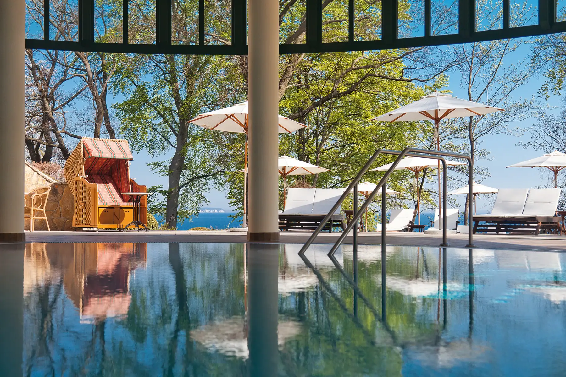 A pool with a deckchair and parasols.