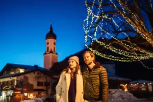 A man and a woman stand in front of an illuminated tree.