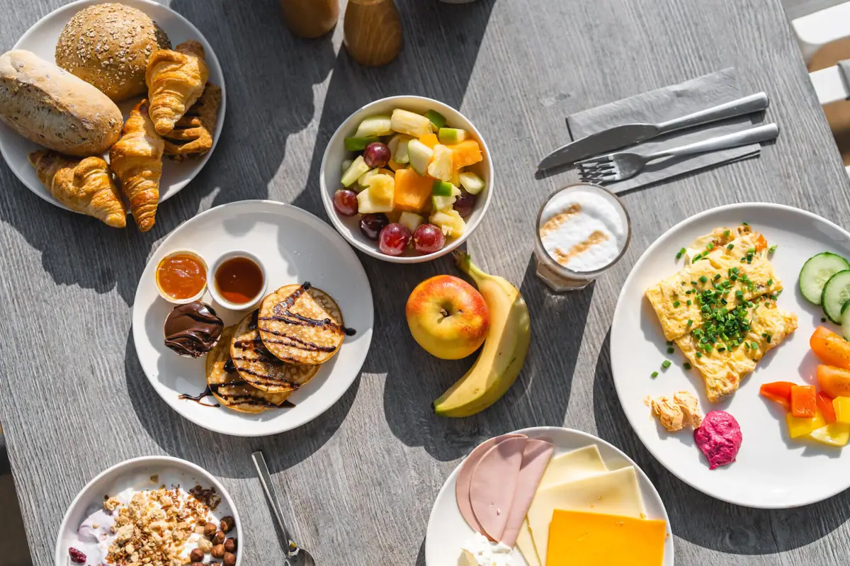 A table with plates full of food and fruit.