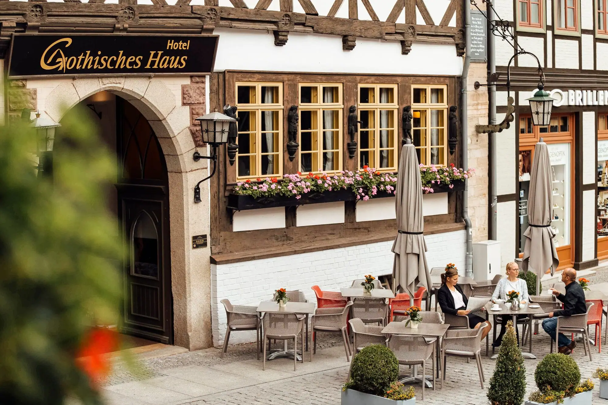 A group of people sit at outdoor tables in front of a building.