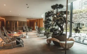 Relaxation room in the SPA area of the aja Werfenweng with lots of loungers and plants in a light-flooded room.