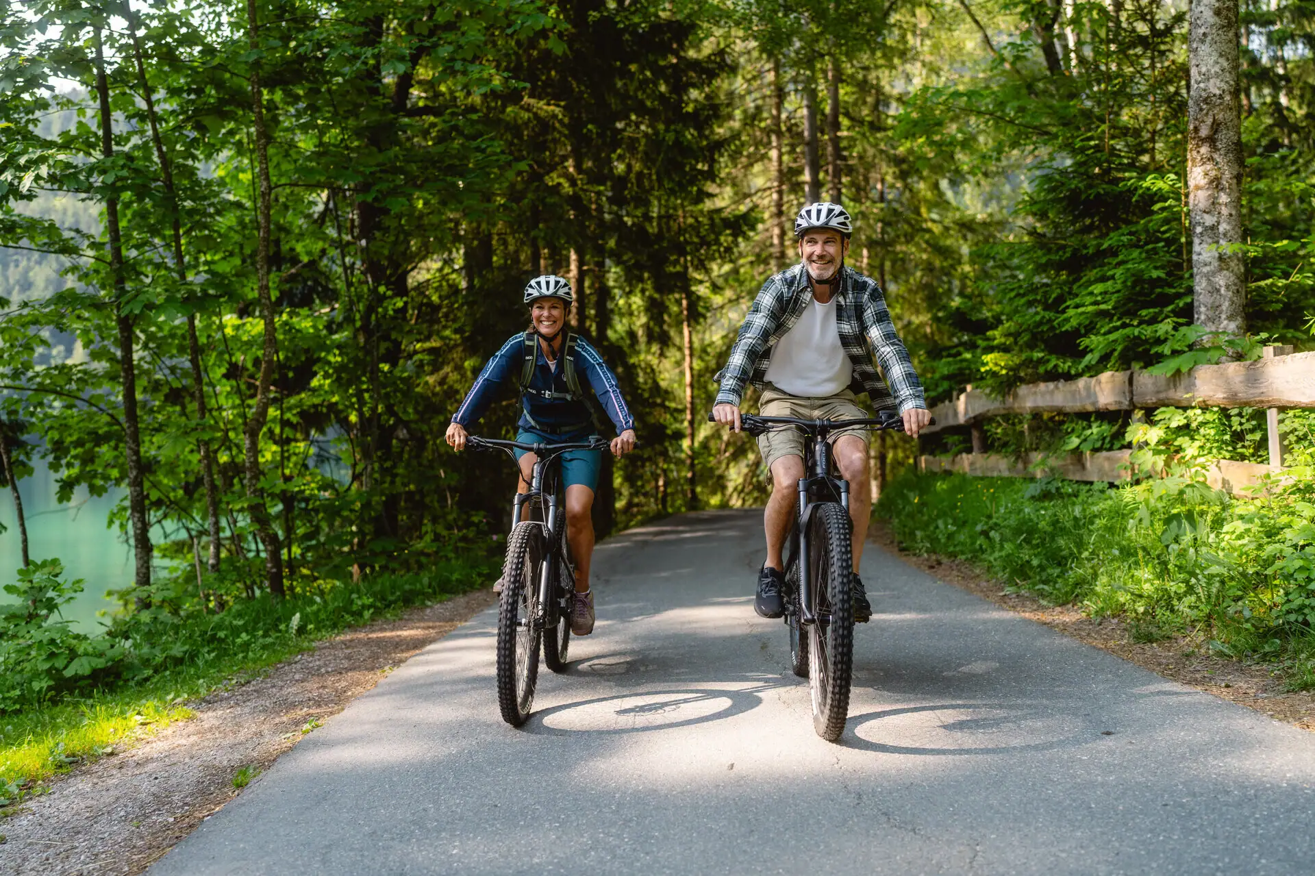 Bike tour A man and a woman are cycling along a path with trees.