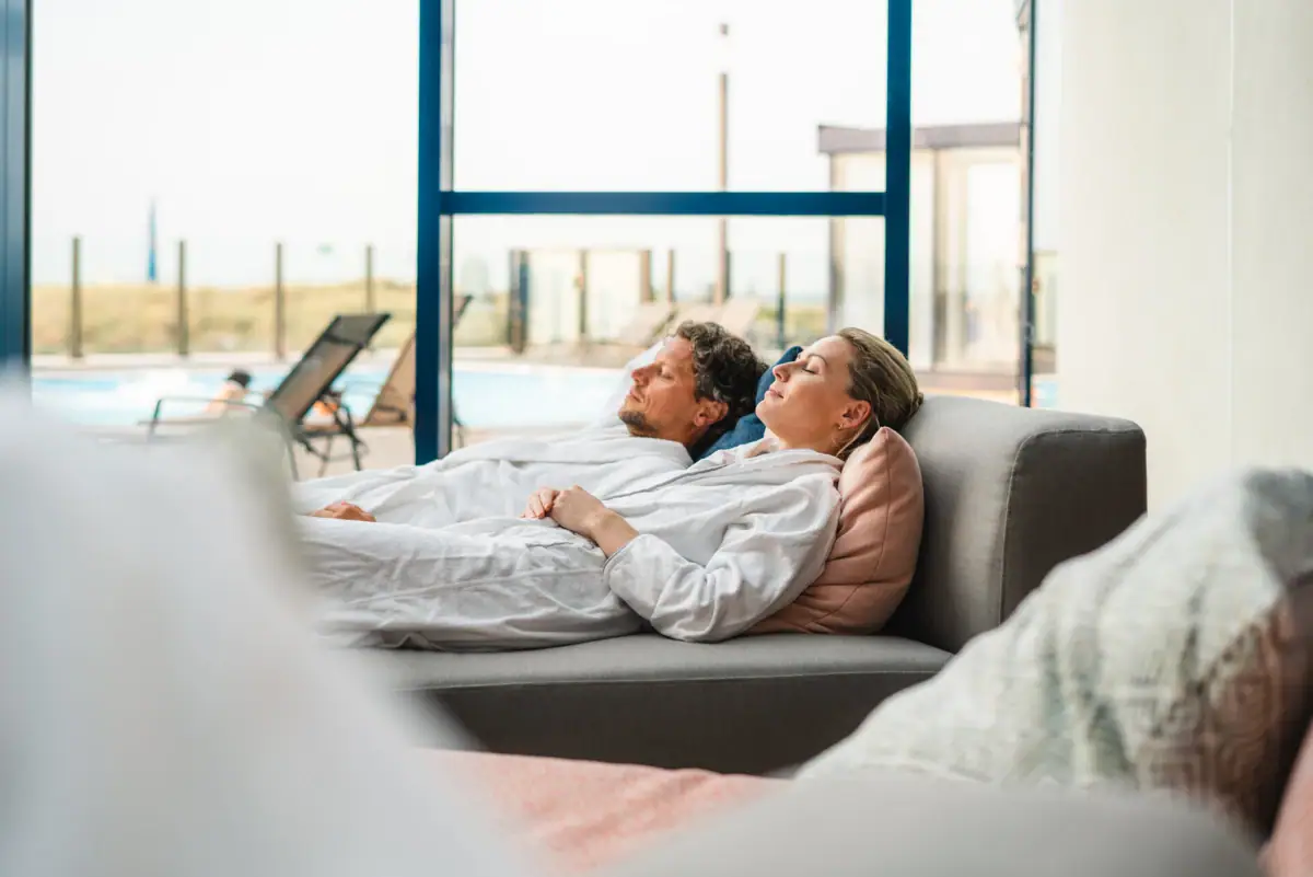 A man and a woman are lying on a sofa.