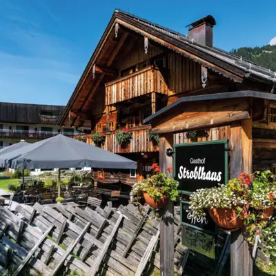 A rustic wooden hut with a sign and parasols.