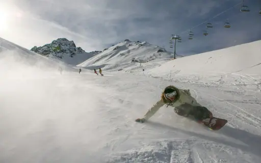 Person on a snowboard riding down a snowy slope.