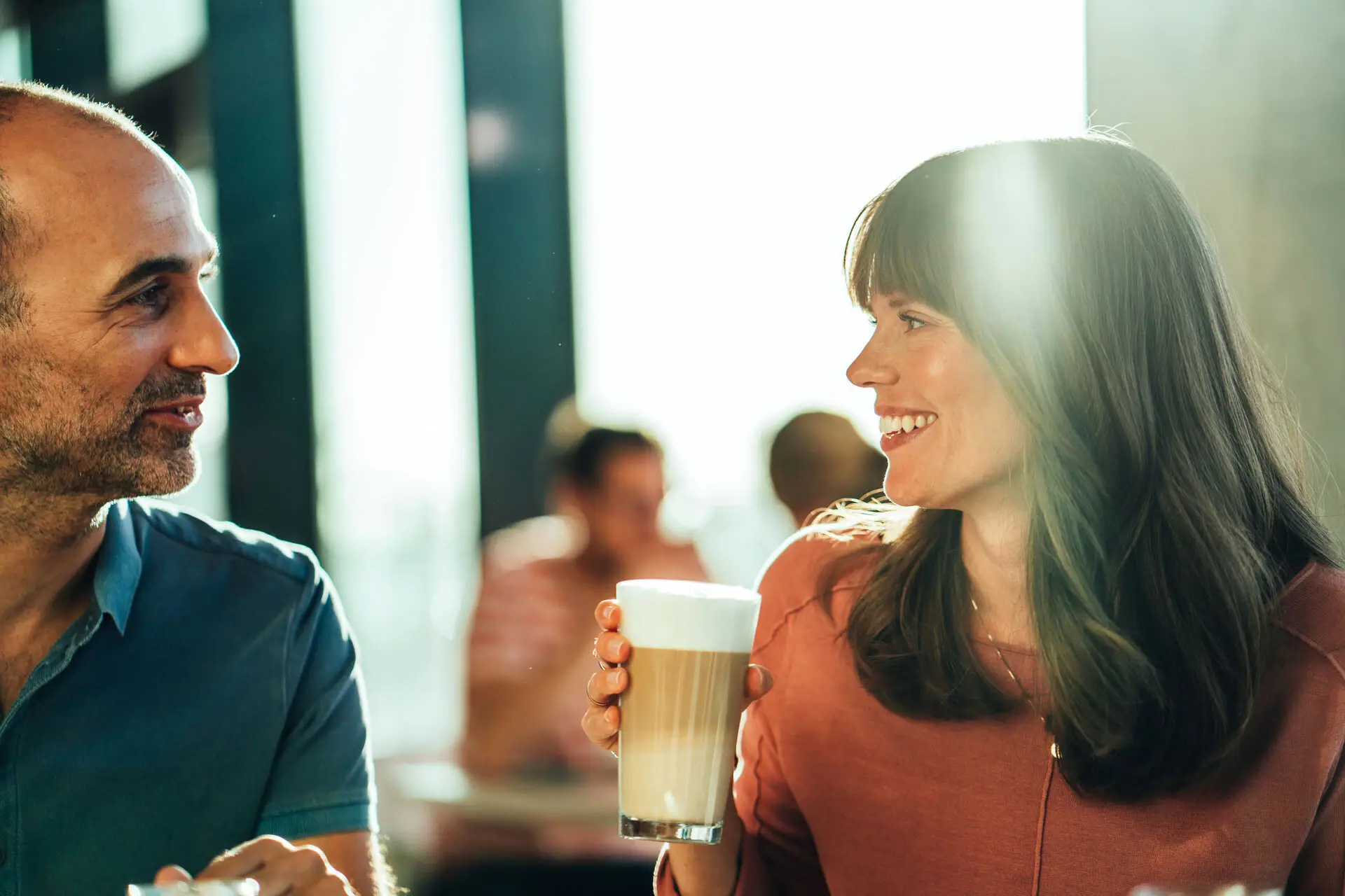 A man and a woman are holding a glass of coffee.