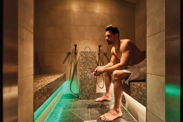 A man sits on a bench in a steam bath.