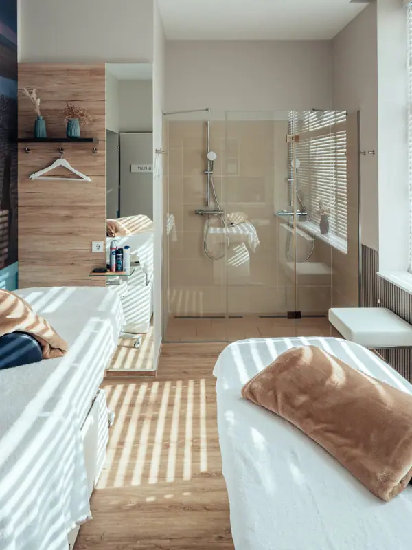 Ein Zimmer mit zwei Betten und einer Dusche.