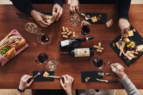 A group of people eat at a table with wine glasses and food.