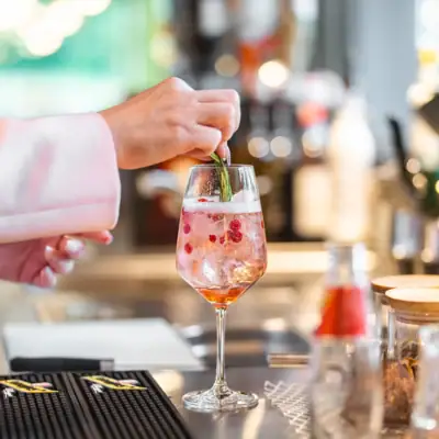 One person places a leaf on a drink in a wine glass.
