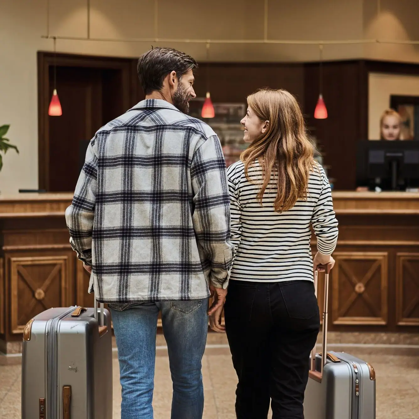 A man and a woman with luggage in a hotel lobby.