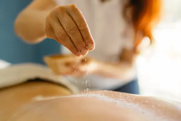 One person sprinkles salt on the back of another person.