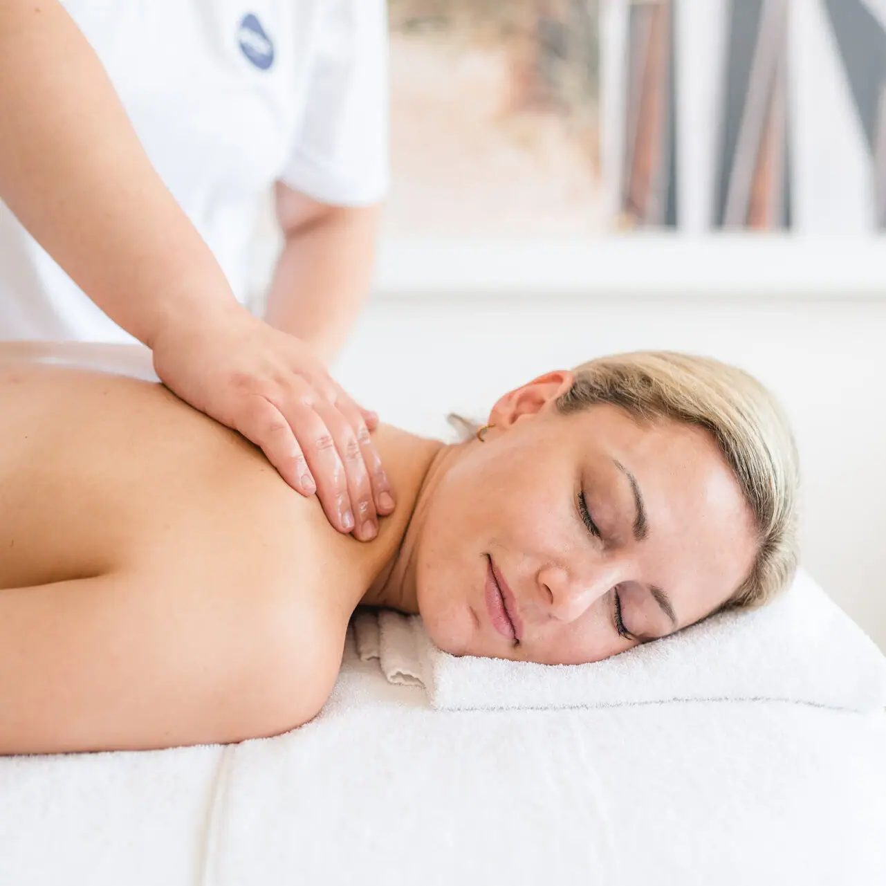 Massage A woman lies on a white towel with her eyes closed.