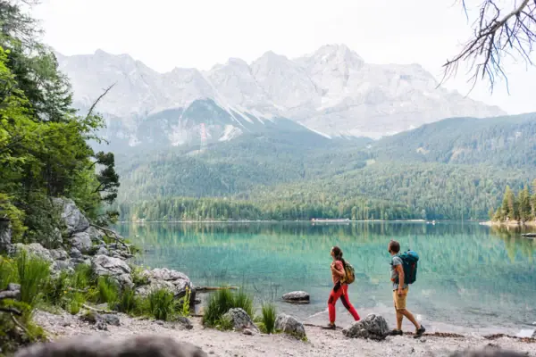 Hiking at the Eibsee A man and a woman are walking along a lake.