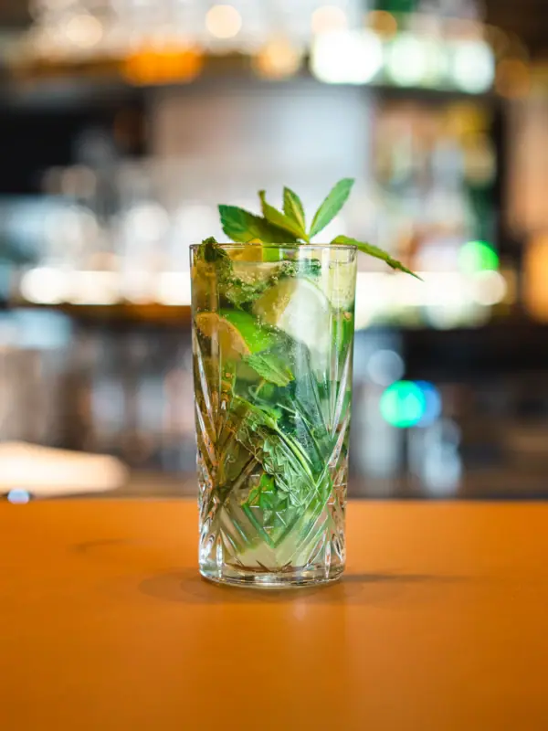 A glass with a drink garnished with limes and mint leaves in the aja Bar Garmisch-Partenkirchen.