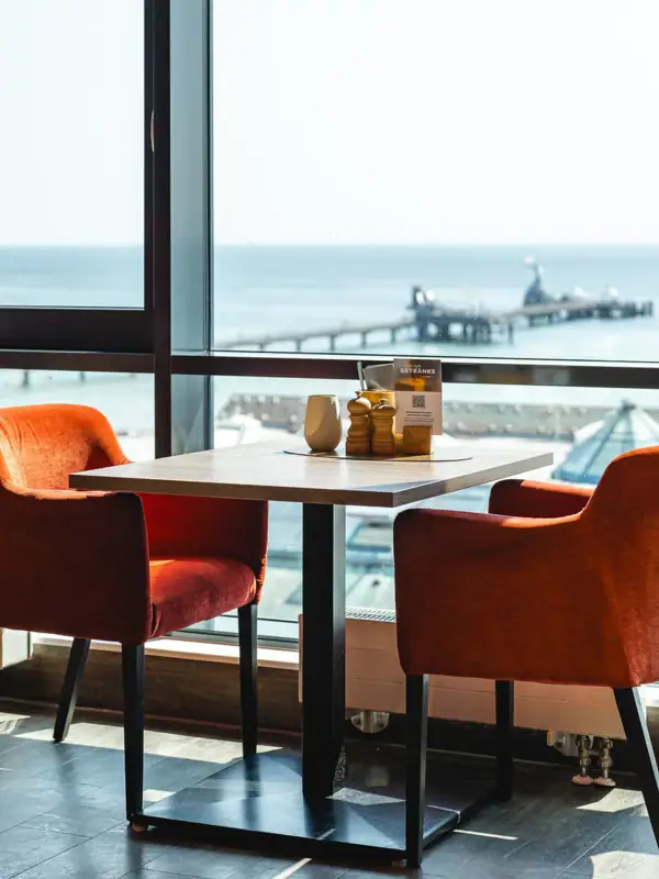 A table with chairs and a view of the ocean.