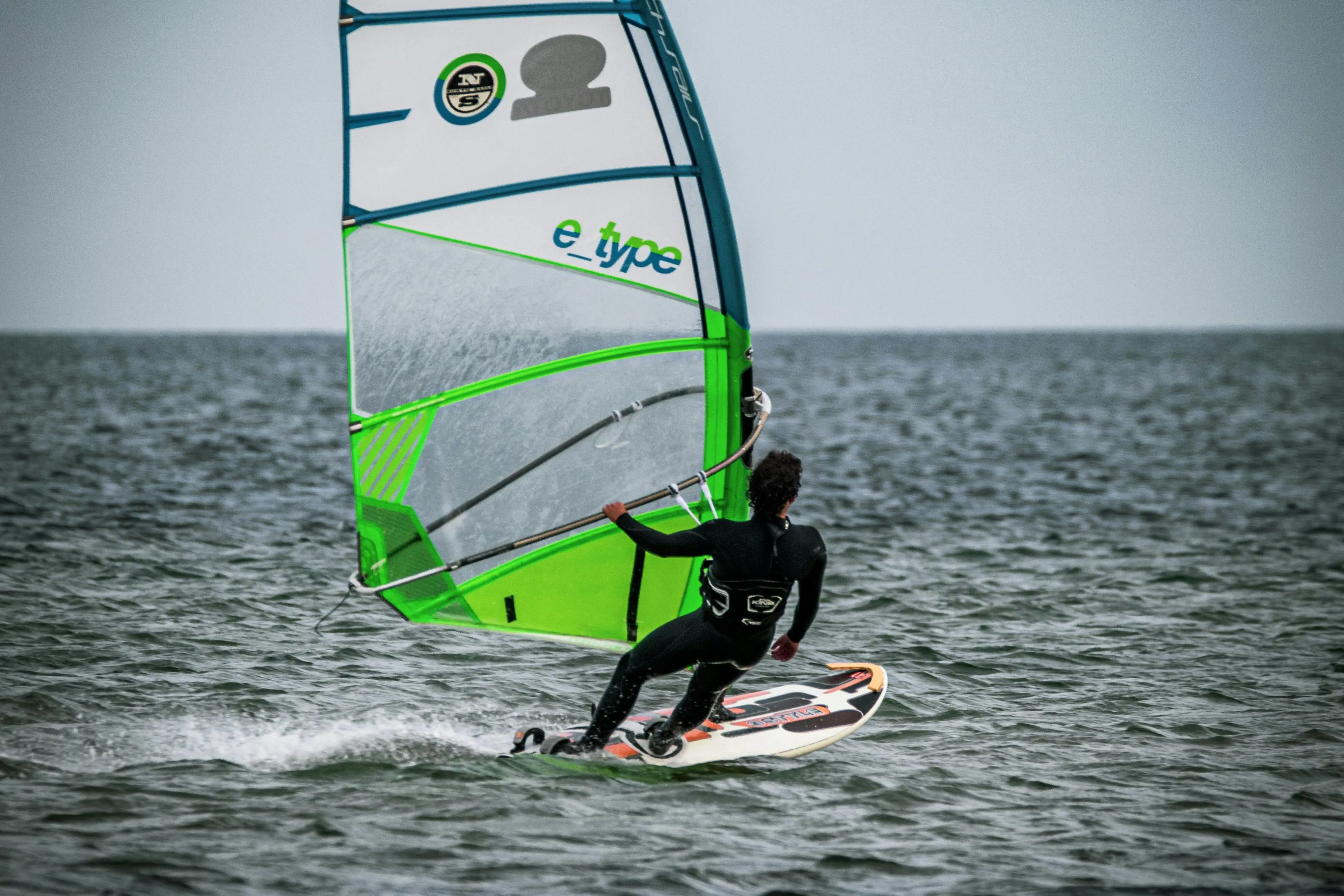 A person on a surfboard with a sail.