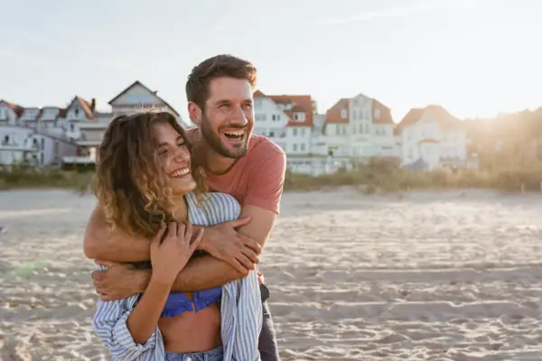 A man and a woman embrace on the beach.