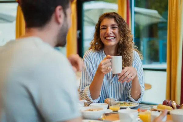 A woman holding a mug with a smiling man.