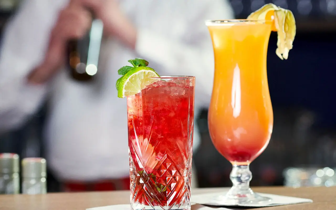 There are two cocktail glasses on a bar table