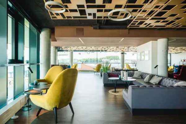 A room with a yellow chair and tables.