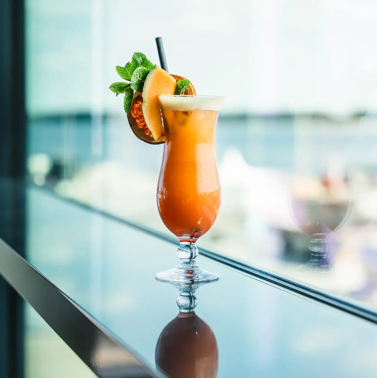 A glass with a cocktail and garnish on a table.