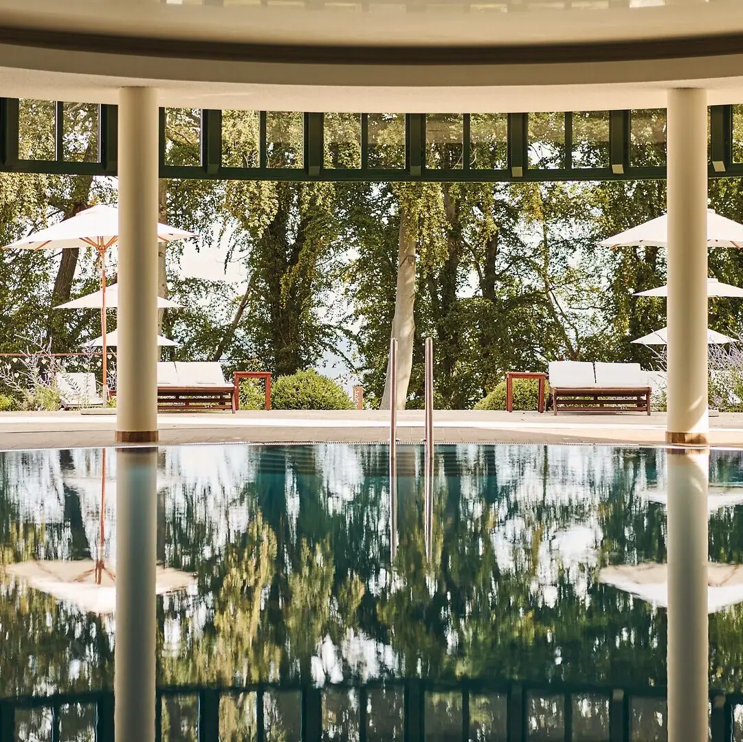 A pool with parasols and chairs in the background.
