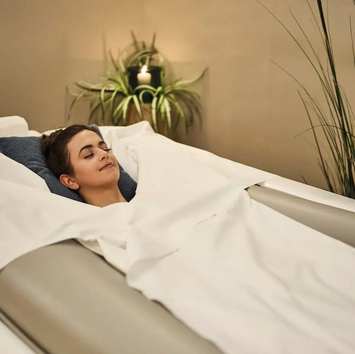 A woman lies in a bed on a soft pack couch