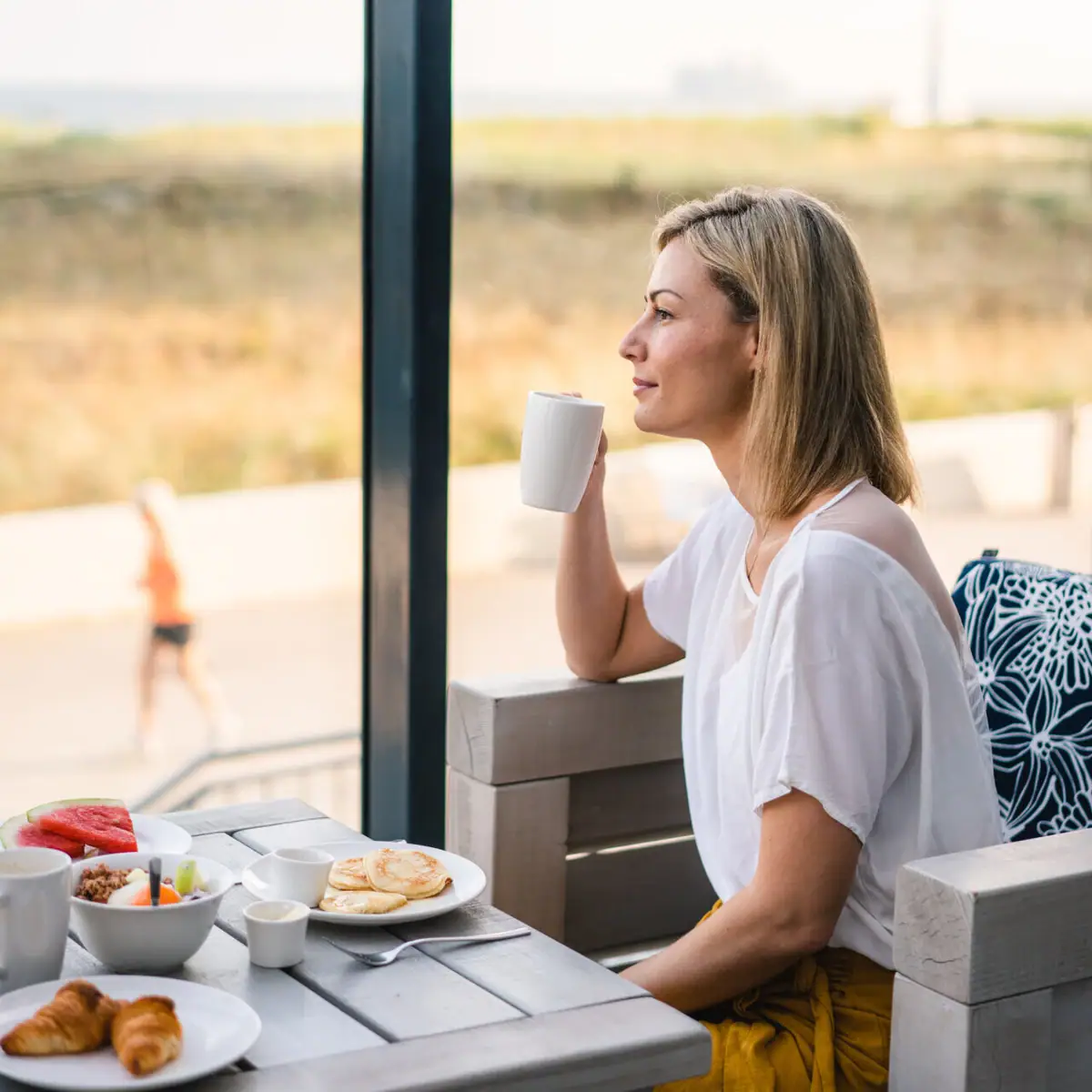 A woman sits at a table with food on it.