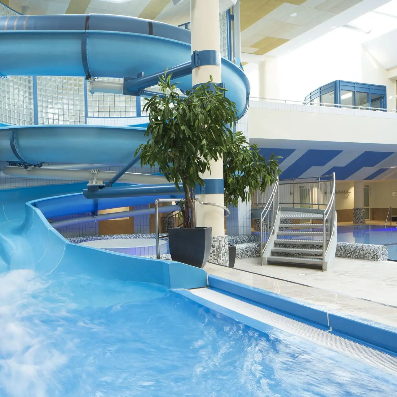 Water slide in a building with a swimming pool.
