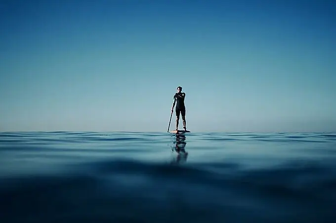 A person on a paddleboard in the ocean.