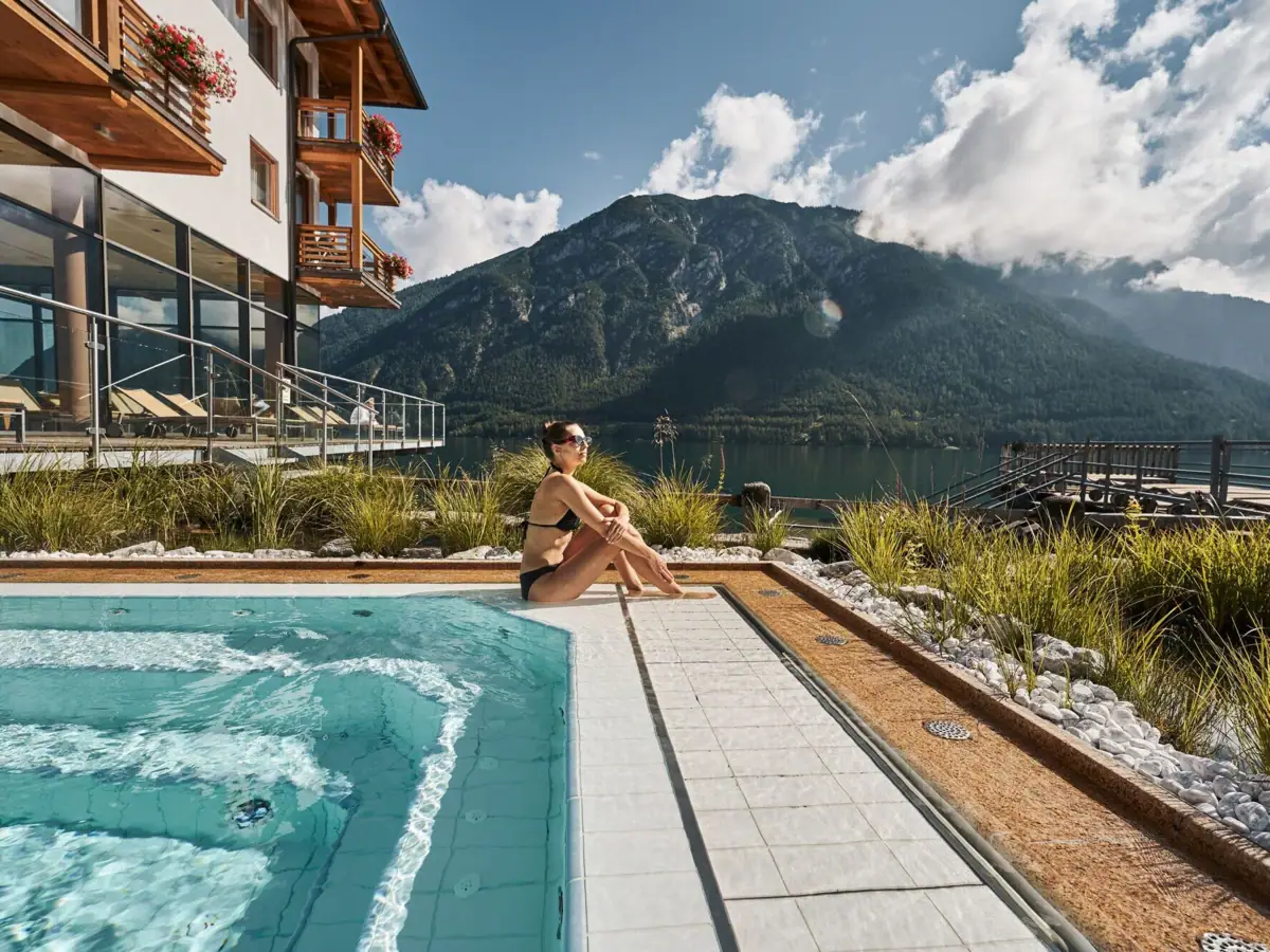 Whirlpool with a view of Lake Achensee A woman sits by a pool with a mountain in the background.